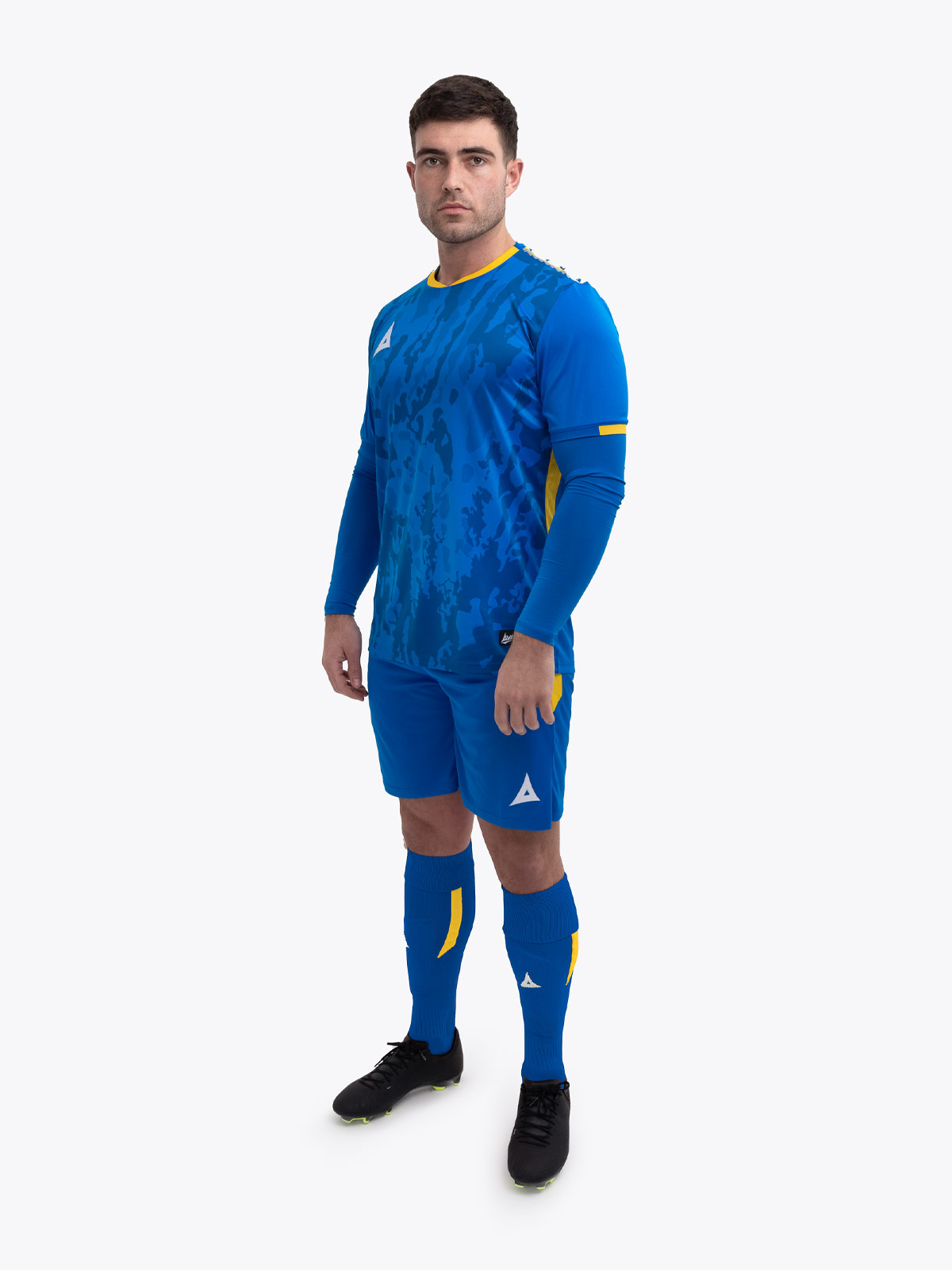 a model standing up wearing a royal blue and yellow football shirt, blue shorts and blue football socks.