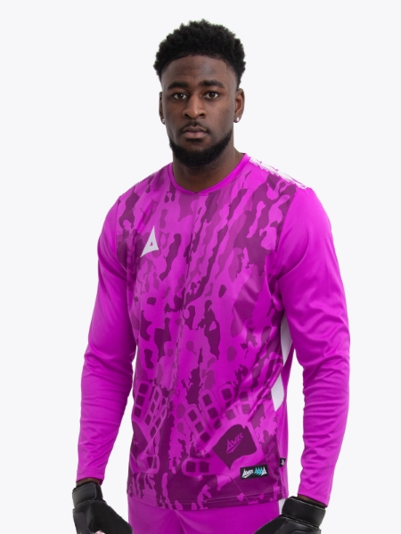 A model standing up wearing a magenta goalkeeper football shirt with a camo pattern