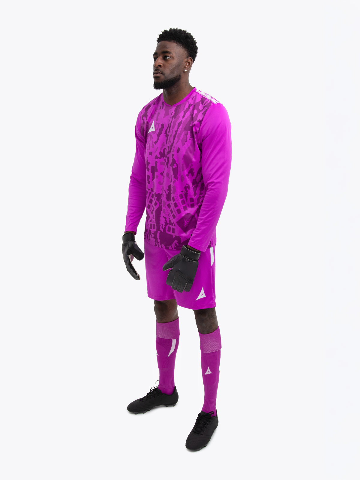 a model is wearing a magenta goalkeeper football shirt. the football shirt has a camo pattern